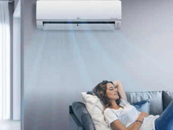 Woman relaxing on a couch beneath a running LG split system air conditioner in a modern residential living room