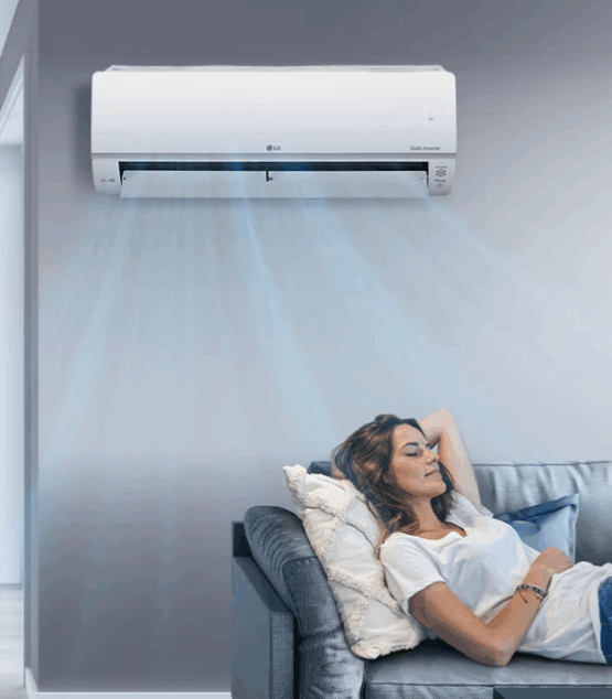 Woman relaxing on a couch beneath a running LG split system air conditioner in a modern residential living room