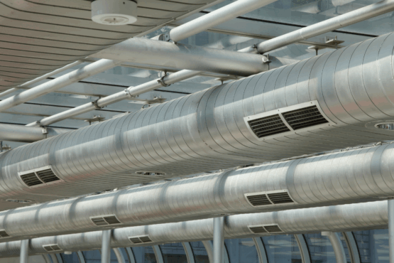Commercial ducted air conditioning system with large cylindrical air vents suspended from ceiling supports
