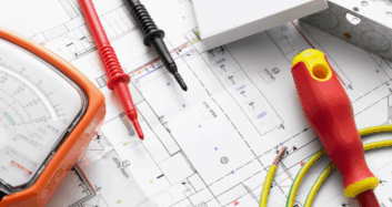 Electrical tools and circuit tester laid out on top of building plans for system design and installation