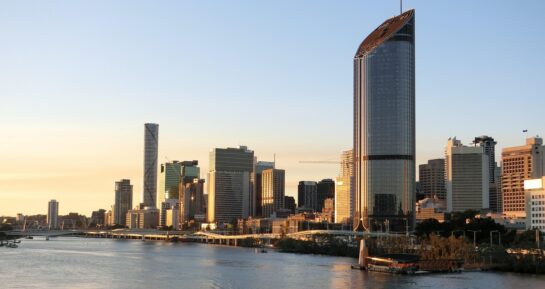 Brisbane skyline at sunset overlooking the Brisbane River and modern city buildings.